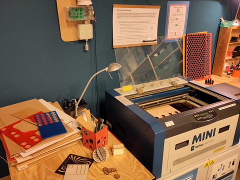Maschine mit einer Glasplatte oben, daneben ein Schreibtisch mit Materialien